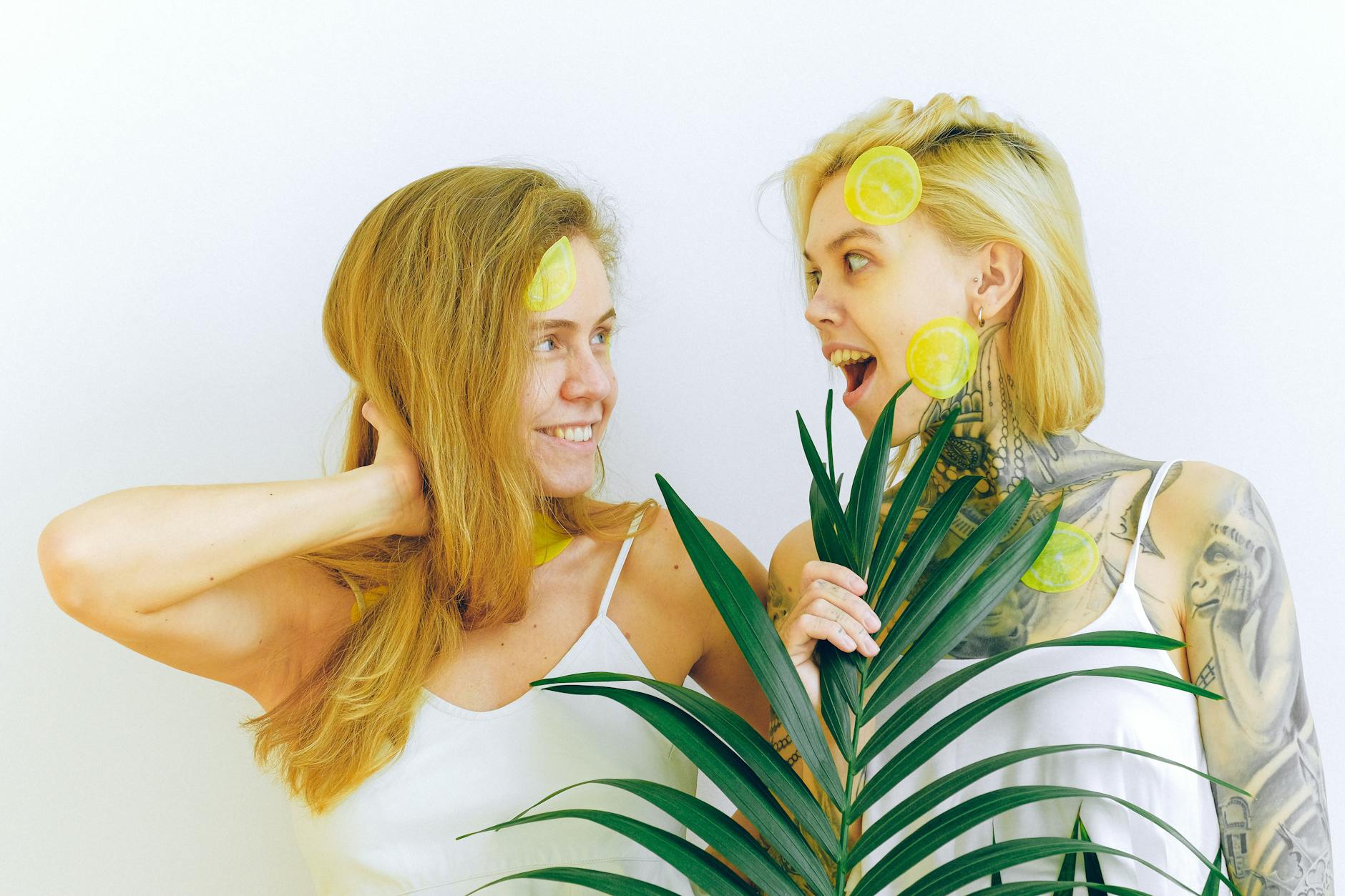 Two women smiling with fresh lemons, expressing joy and calm presence indoors.