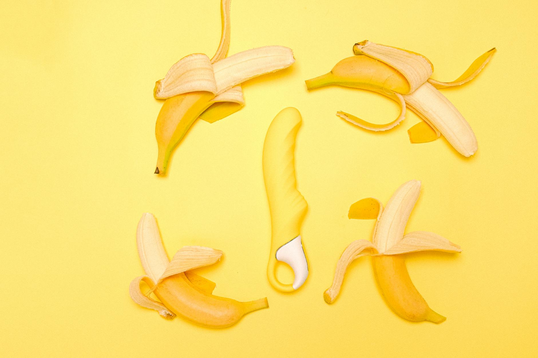 A yellow lemon vibrator surrounded by fresh lemons on a bright yellow background.