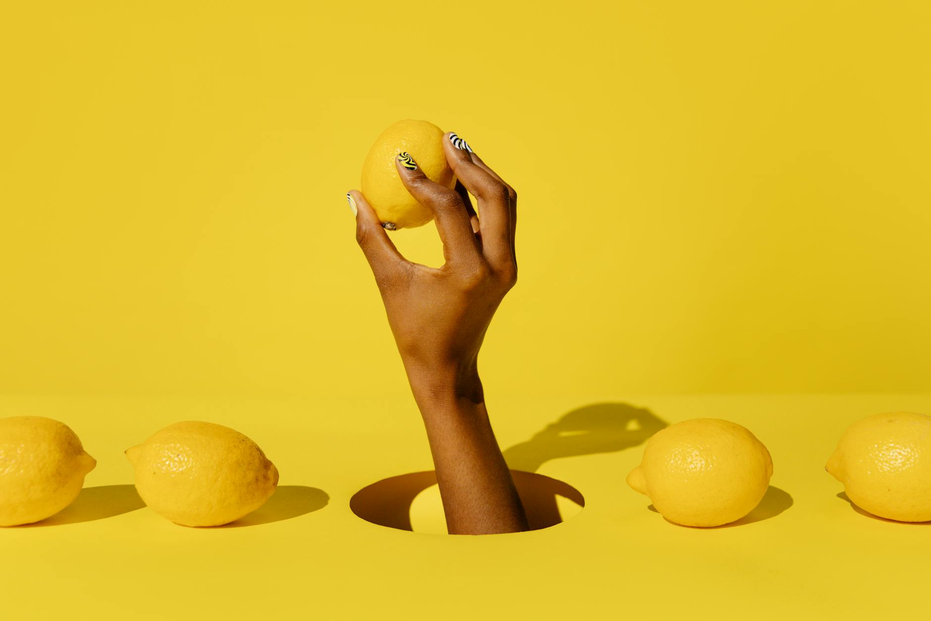 A yellow silicone vibrator surrounded by fresh lemons on a yellow background, illustrating comfort and natural sensation