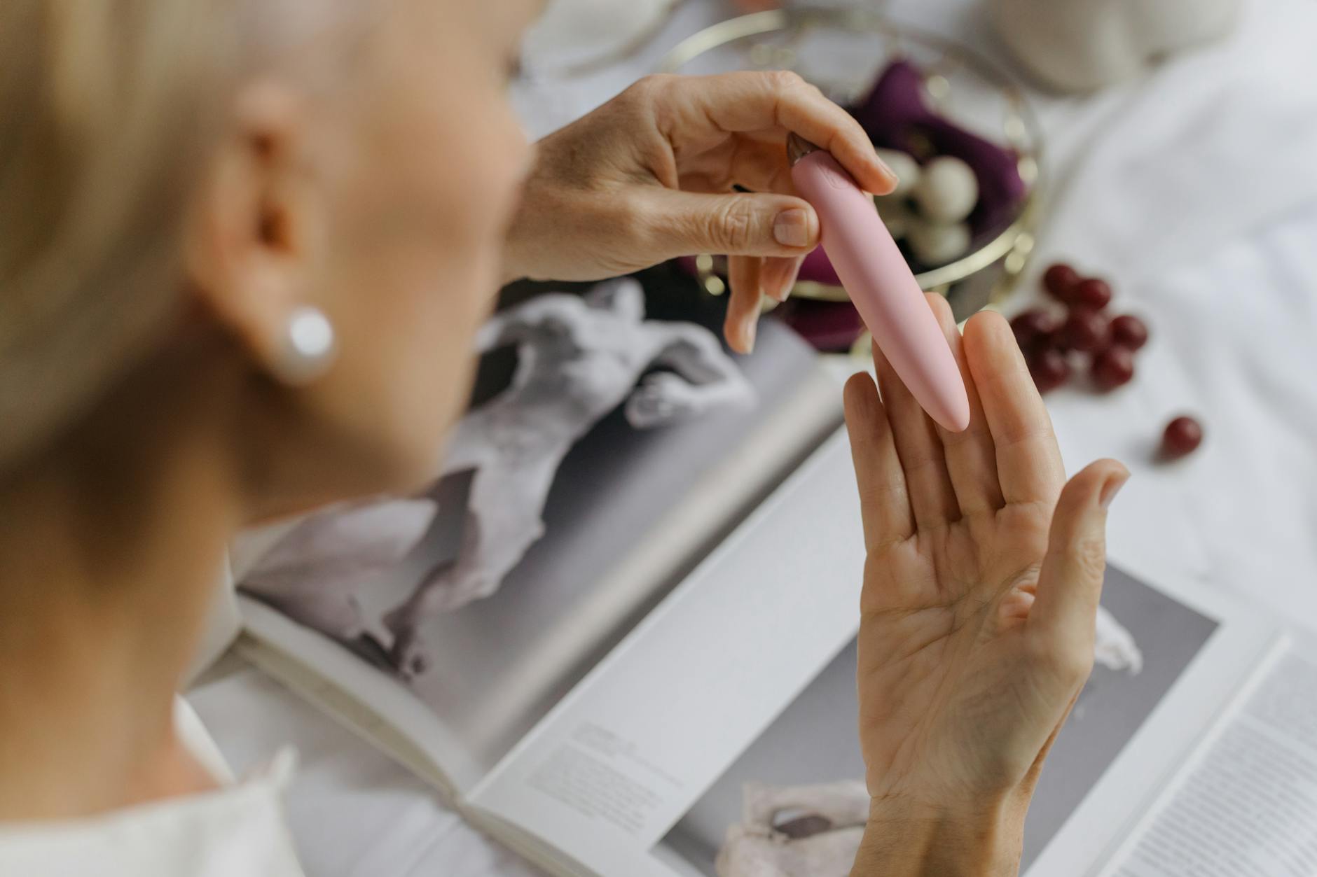 Close-up of hands holding a pink vibrator, emphasizing intimate personal exploration.