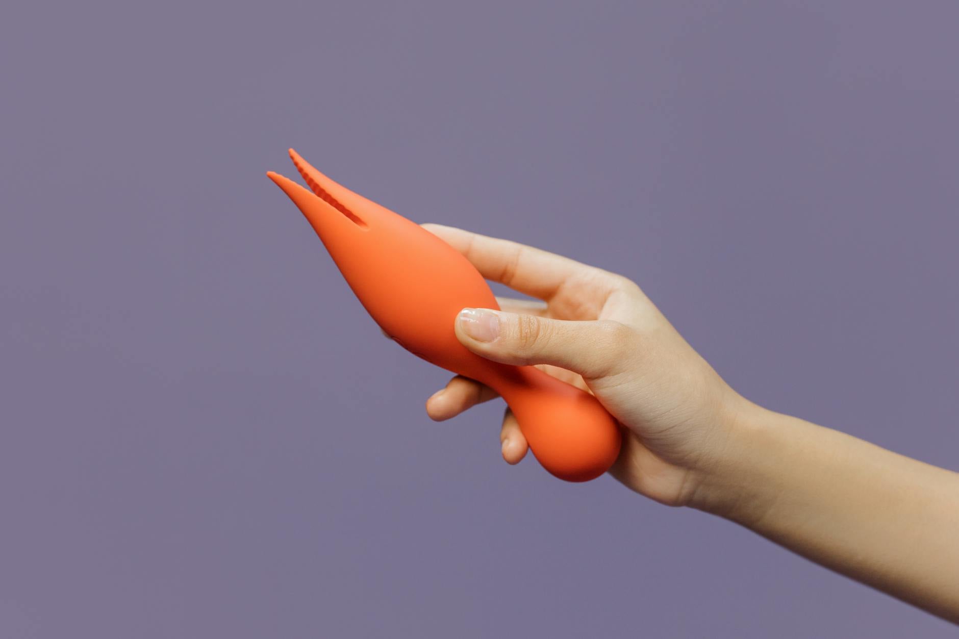A hand holding a lemon vibrator against a minimalistic backdrop, demonstrating sensual product design