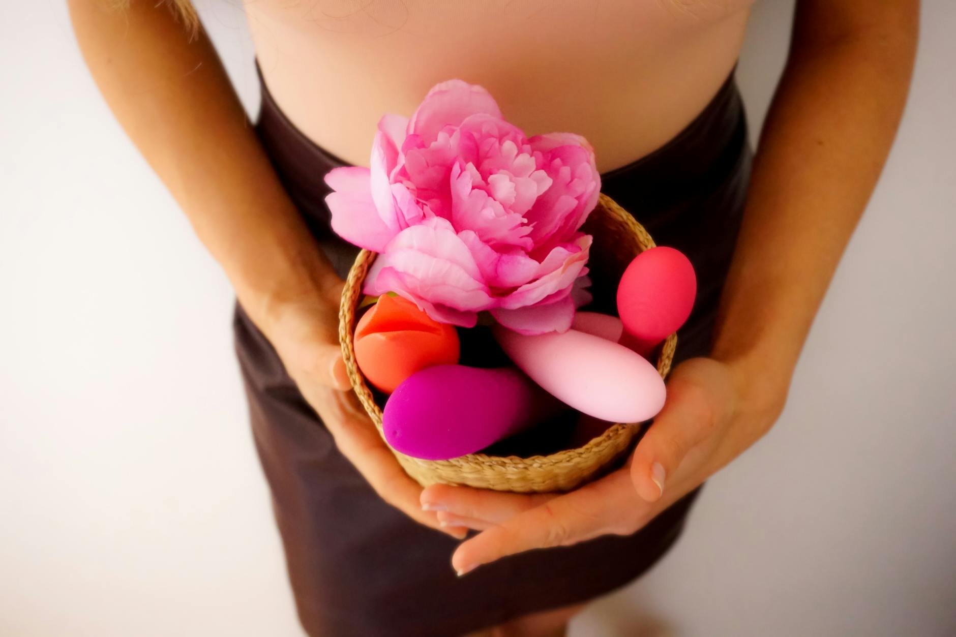 A woman with eyeglasses holds two colorful vibrators, representing confidence and openness about pleasure in relationships.